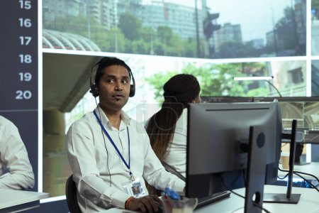 Indian employee following real time traffic activity on CCTV system cameras, registering any illegal driver behavior in the city. Male operator monitoring cars, plate recognition.
