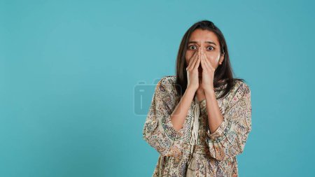 Anxious indian woman covering face with palms, worried about future, isolated over studio background. Tense person shocked by troubling news, gasping, feeling distressed, camera A