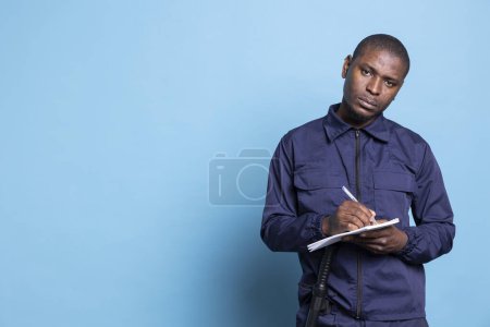 African american bodyguard writing detailed information on his notebook, keeps evidence of all details while he is on protection duty. Male trained agent taking notes to ensure safety.