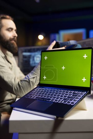 Programmer updating artificial intelligence algorithm using green screen laptop, making it become sentient. IT specialist programming self aware AI with mockup notebook
