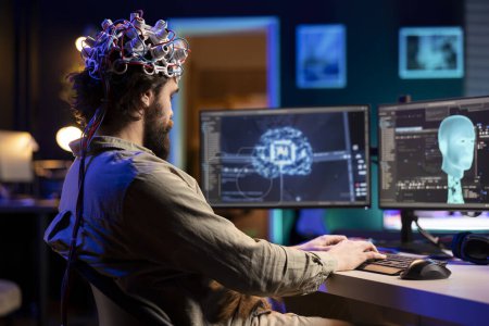 Developer with EEG headset on programming brain transfer into computer virtual world, becoming one with AI. Transhumanist using neuroscientific tech to transcend physical limitations