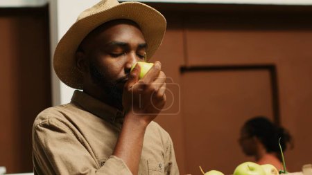 Männliche Kunden genießen den frischen Duft von grünen Äpfeln in Kisten und kaufen Obst und Gemüse im örtlichen Null-Abfall-Ökomarkt. Junge Erwachsene riechen natürliche Bio-Aroma von Produkten. Kamera 1.