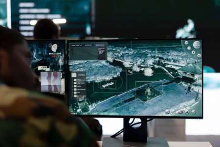 Le recruteur analyse les images de vidéosurveillance radar satellite dans la salle de contrôle, surveillant l'unité d'infanterie pendant une bataille. Soldat de l'armée travaillant au poste de commandement de la division de reconnaissance et défense.