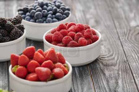 Foto de Mix of berries on the table, fortified breakfast of ripe berries, blueberries, gooseberries, raspberries, black currants, taken from the top angle - Imagen libre de derechos