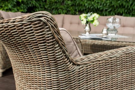 armchair with wicker seat and dining table, outdoor furniture against stone wall background