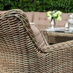 armchair with wicker seat and dining table, outdoor furniture against stone wall background