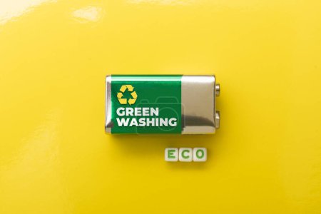 Foto de Concepto Greenwashing: batería sobre fondo amarillo y matriz que compone la palabra eco - Imagen libre de derechos