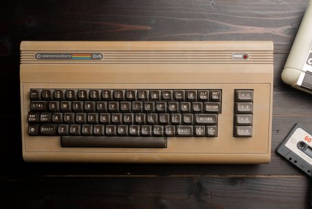 Foto de Carrara, Italia - 18 de marzo de 2023 - Commodore 64 ordenador con cassette player en mesa de madera - Imagen libre de derechos