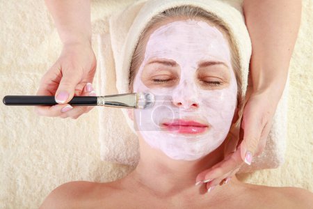 Disfrute de la relajación: Retrato tranquilo de una mujer que se aplica una máscara facial en el spa. Descubre la serenidad del autocuidado y realza tu belleza natural.