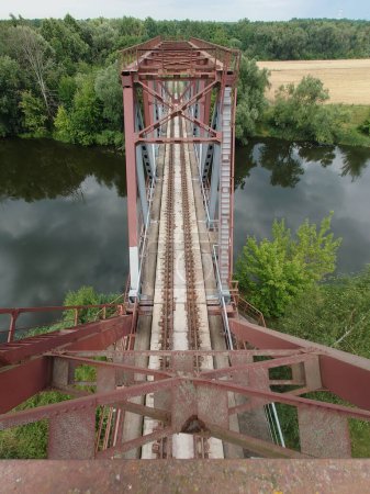 Téléchargez les photos : Vue de dessus d'un pont ferroviaire en béton armé traversant une rivière sur les rives de laquelle se trouve une végétation dense en été - en image libre de droit