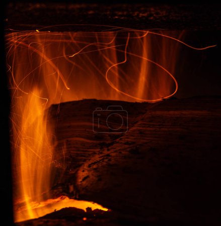 Foto de Movimiento de chispas de troncos ardiendo en una estufa rústica - Imagen libre de derechos