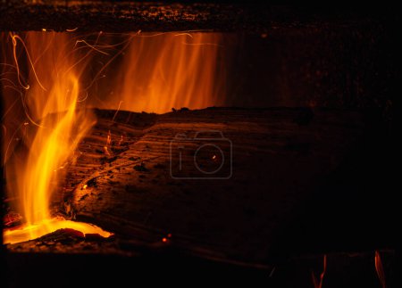 Foto de Primer plano de las partículas de hollín y la trayectoria de las chispas de la quema de un tronco en una estufa rústica - Imagen libre de derechos