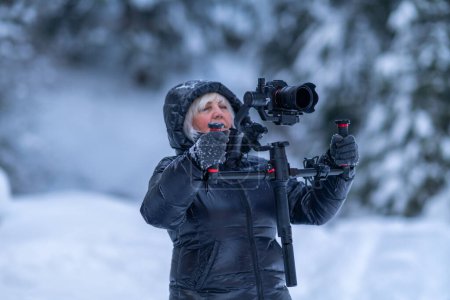 A lady films a winter forest and uses a Steadicam for this.