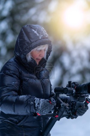 A female operator monitors the camera's operation while shooting video using a stabilizer.