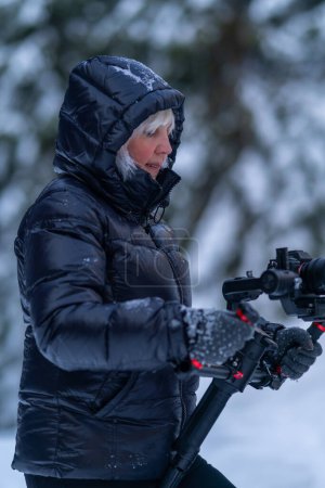 A woman looks at the display of a camera mounted on a stabilizer