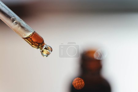 Open amber bottle with dropper with serum or essential oil. Skincare products, natural cosmetic on white background. Medicine and beauty concept for face care. Selective focus on pipette