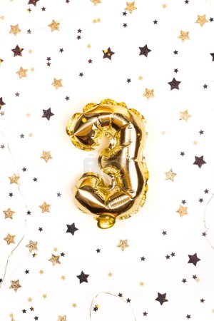 Téléchargez les photos : Ballon d'hélium doré numéro 3. Guirlande festive aux étoiles confettis. Carte de voeux d'anniversaire. Contexte du troisième anniversaire - en image libre de droit