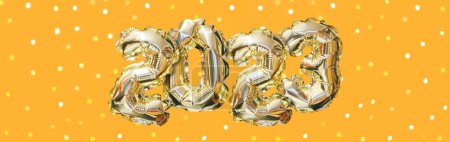 Téléchargez les photos : Hélium nombre de ballon doré de l'année 2023. Guirlande festive rayonnante avec bokeh sur fond orange. Bannière Bonne Année - en image libre de droit