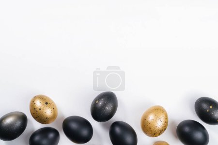 Foto de Huevos pintados de oro y negro sobre fondo blanco. Concepto mínimo de Pascua con espacio de copia para texto. Fondo de lujo dorado - Imagen libre de derechos