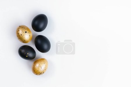 Foto de Huevos pintados de oro y negro sobre fondo blanco. Concepto mínimo de Pascua. Fondo de lujo dorado con espacio de copia para texto. - Imagen libre de derechos