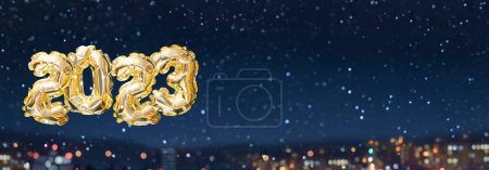 Foto de Helio número globo de oro del año 2023 en el contexto de la ciudad nevada noche. Guirnalda festiva brillante con bokeh. Feliz Año Nuevo tarjeta de felicitación - Imagen libre de derechos