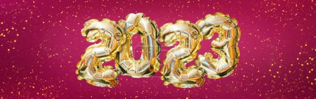 Téléchargez les photos : Hélium nombre de ballon doré de l'année 2023. Guirlande festive rayonnante avec bokeh sur fond de magenta. Bonne année carte de voeux - en image libre de droit