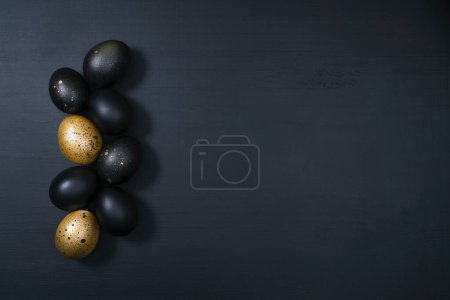 Foto de Huevos pintados de oro y negro sobre fondo de madera oscura. Concepto mínimo de Pascua. Fondo de lujo con espacio de copia para texto. - Imagen libre de derechos