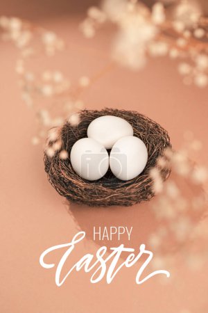 Photo for Easter concept with Happy Easter lettering. Eggs on a beige background. Nest containing three white egg. - Royalty Free Image
