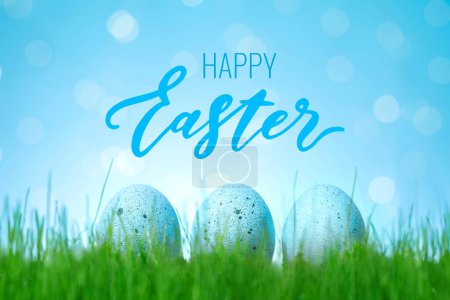Téléchargez les photos : Postcard or flyer with Happy Easter lettering. Decorated Easter blue eggs in grass. Concept of Easter egg hunt. - en image libre de droit