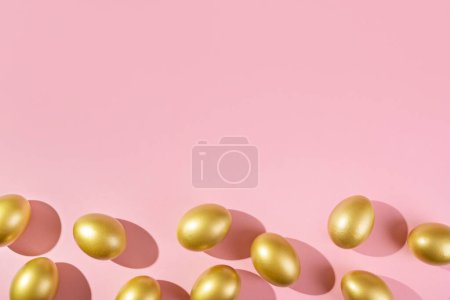 Foto de Plantilla de Pascua con borde de huevo dorado. Huevos pintados de oro sobre fondo rosa. Concepto de Pascua con espacio de copia para texto. Diseño minimalista de estilo laico plano. - Imagen libre de derechos