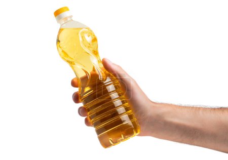 Téléchargez les photos : Une bouteille d'huile de tournesol dorée à la main. Produit sur fond blanc isolé sans étiquette. L'huile de tournesol provient des graines de tournesol. - en image libre de droit