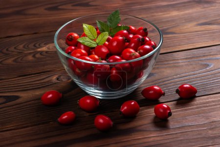 Photo for Fresh red Rose Hips in the glass bowl on wooden background, fresh Berries from the dog rose. - Royalty Free Image
