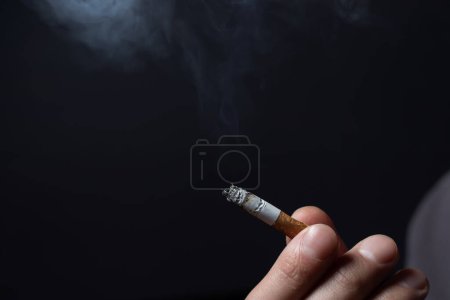 Photo for Smoking cigarette in the hand of young man close up. - Royalty Free Image