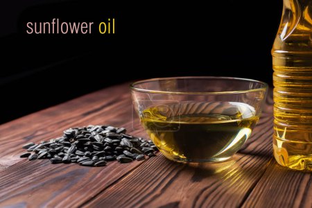 Photo for Sunflower oil in bottle and glass bowl with seed pile on wooden desk. - Royalty Free Image