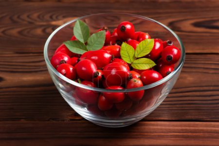 Photo for Fresh red Rose Hips in the glass bowl on wooden background, fresh Berries from the dog rose. - Royalty Free Image