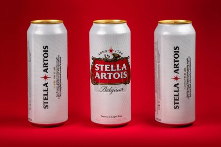 Photo for Ukraine. Dnipro. 20 march 2023: Three white can of great Belgium beer Stella Artois on red background. Alluminium can of Stella Artois beer on black background. - Royalty Free Image