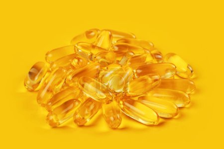 Photo for Fish oil capsules with omega 3 and vitamin D on yellow background. - Royalty Free Image