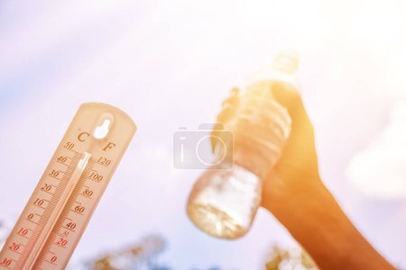 Photo for Hot temperature,Thermometer and water bottle on sky with sun shining in summer show higher Weather, concept global warming. - Royalty Free Image