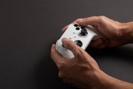 Photo for White next gen controller in man hands on dark background. - Royalty Free Image