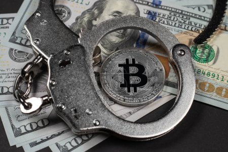Photo for Symbolic coins of bitcoin and stack of bitcoin coins and metall handcuffs on banknotes of one hundred dollars. Exchange bitcoin for a cash dollar, but be a law-abiding citizen. - Royalty Free Image