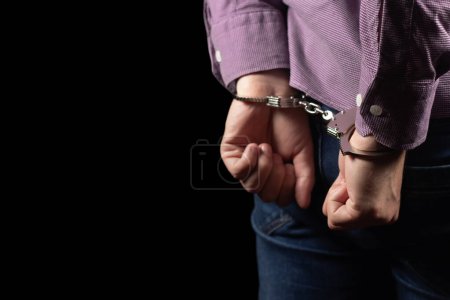 Photo for Arrested man in handcuffs with handcuffed hands behind back in prison. - Royalty Free Image