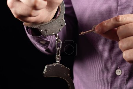 Großaufnahme der Hand von Polizeibeamten Handschellen an männlichen Angeklagten entriegeln Hand für Hand, Fokus auf Schlüsselfessel.