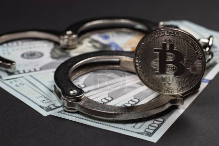 Photo for Symbolic coins of bitcoin and stack of bitcoin coins and metall handcuffs on banknotes of one hundred dollars. Exchange bitcoin for a cash dollar, but be a law-abiding citizen. - Royalty Free Image