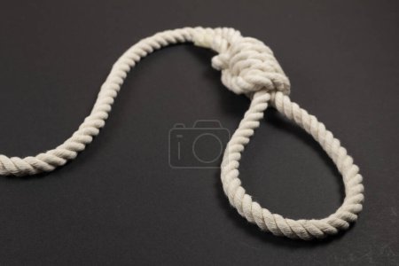 Rope noose for hangman, suicide made of natural fiber rope on dark background. Hemp rope noose for homicide or commit suicide concept. Hang rope knot for gallows and Hang mans real