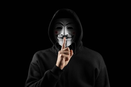 Photo for Dnipro. Ukraine 31 jan 2024: Man wearing vendetta mask with hoodie puts a finger to his lips showing a symbol of silence. This mask is symbol for Anonymous hackers group - Royalty Free Image