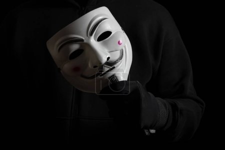 Foto de Dnipro. Ucrania 31 de enero de 2024: Primer plano del hombre con la máscara de Vendetta en la mano. Esta máscara es un símbolo bien conocido para el grupo hacktivista en línea Anónimo. - Imagen libre de derechos