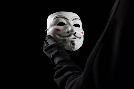 Foto de Dnipro. Ucrania 31 de enero de 2024: Primer plano del hombre con la máscara de Vendetta en la mano. Esta máscara es un símbolo bien conocido para el grupo hacktivista en línea Anónimo. - Imagen libre de derechos