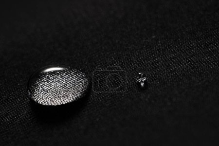Rain water droplets on black fiber waterproof fabric.