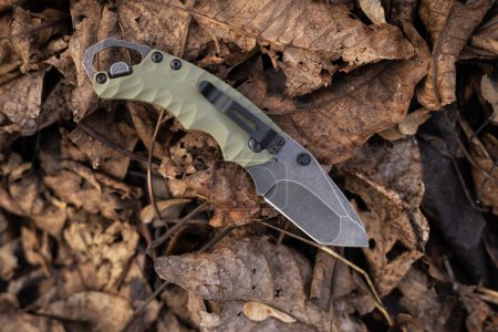 Military tactical knife on dry autumn leaves in the forest.