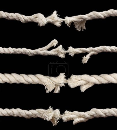 Concept de danger et de risque avec deux extrémités d'une corde usée effilochée maintenue ensemble par le dernier brin sur le point de claquer, sur un fond sombre ou une collection.